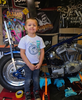 Steve “Skeeter” Wendig's son posing in front of his dad's custom bike